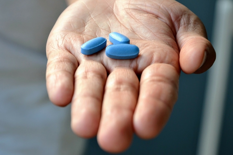 Holding a blue pill in a palm.